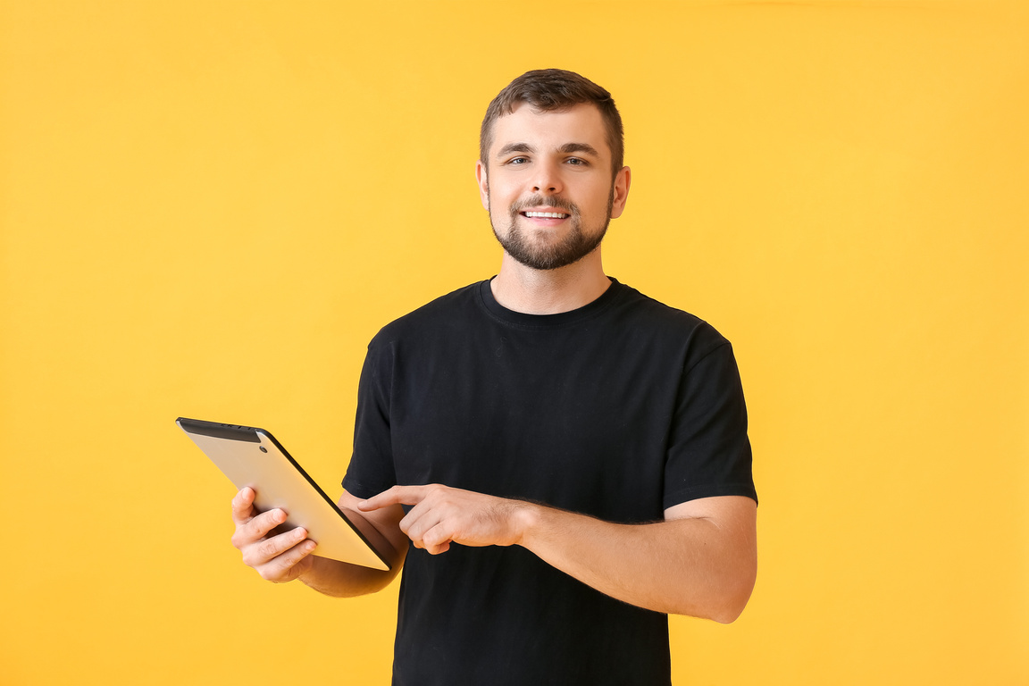 Young Man with Tablet Computer on Color Background